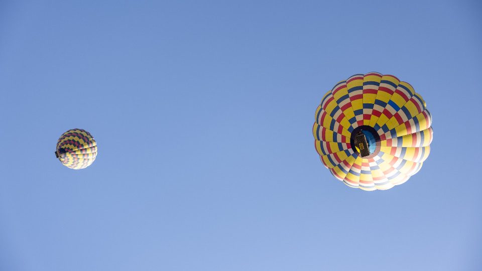 Hot air balloons drifting in a wide blue sky