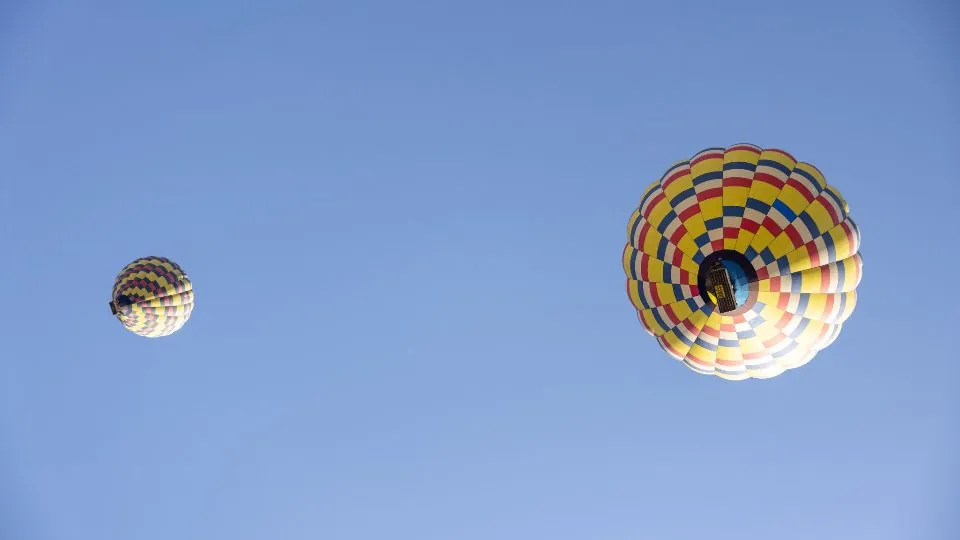 Hot air balloons drifting in a wide blue sky