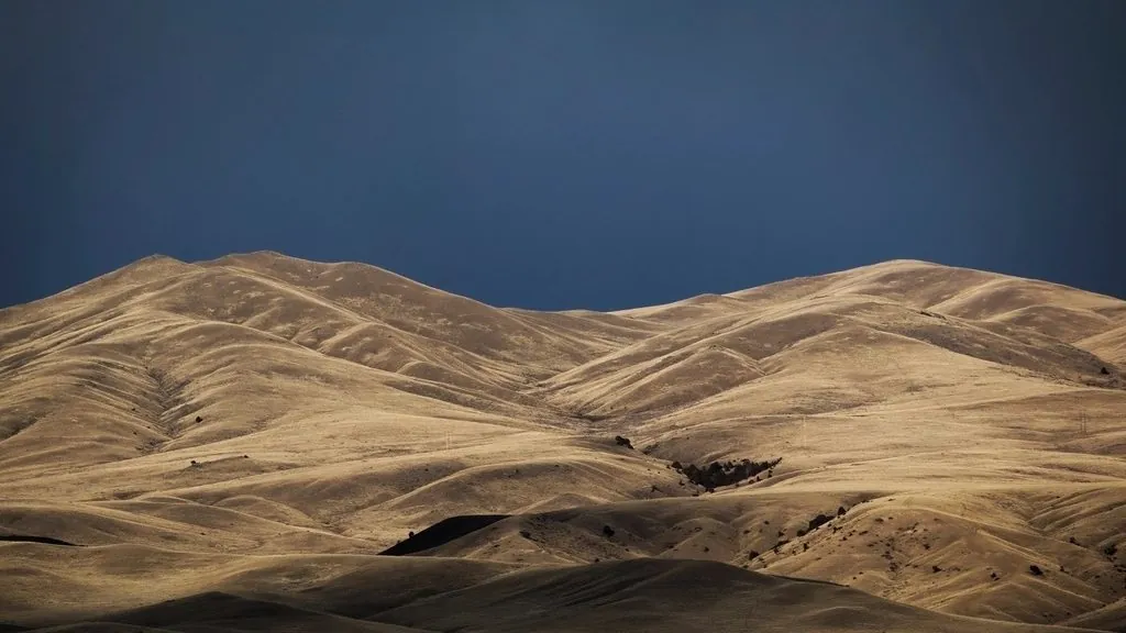 Windswept desert dunes under a dark storm-blue sky