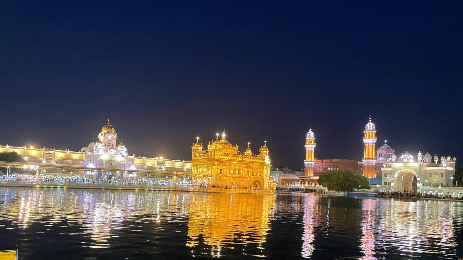 Golden temple glowing over dark water at night