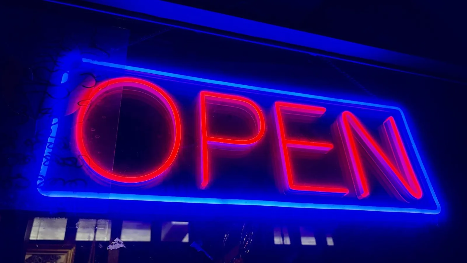 Blue neon sign glowing in a dark window